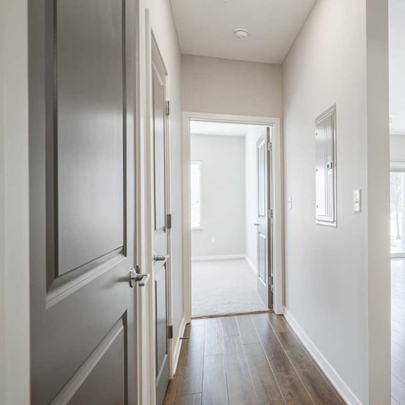 Thumbnail 12 of 19 a hallway with a door open to a bedroom next to a kitchen and living room