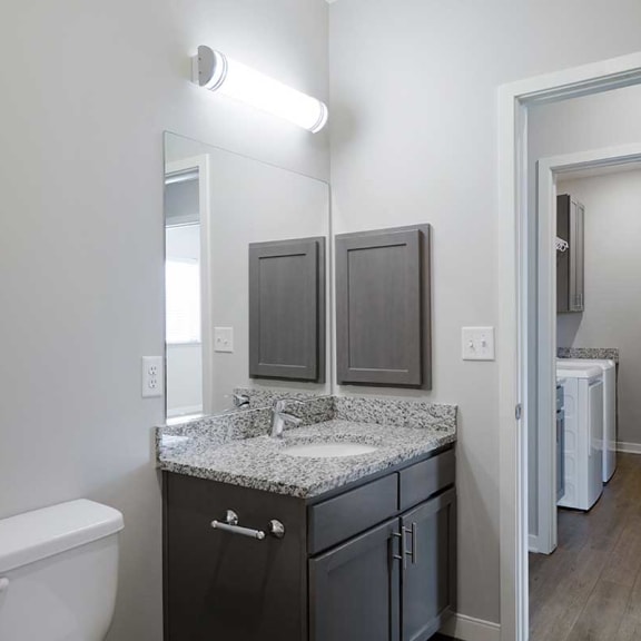 Thumbnail 25 of 27 a bathroom with a sink and a mirror across a hallway from a laundry room