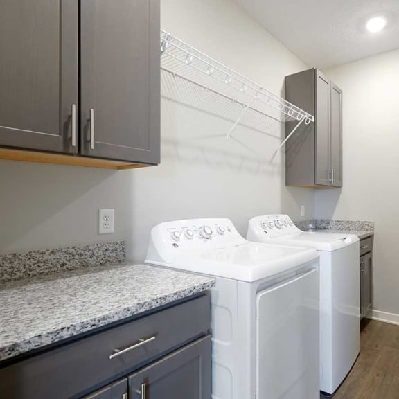 Thumbnail 27 of 27 a large laundry room with a full-sized washer and dryer with over head shelving and cabinet storage