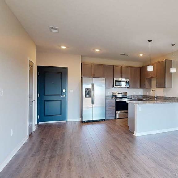 Thumbnail 22 of 29 a kitchen with a peninsula, stainless steel appliances, and grey cabinets extending into a living room