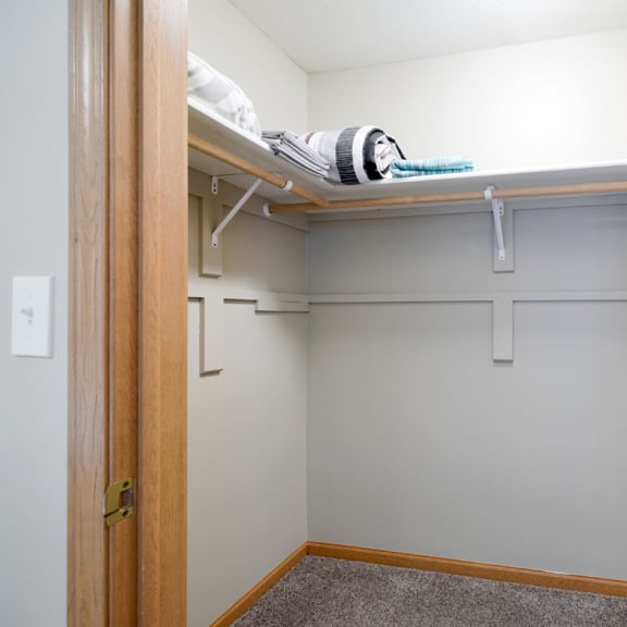 Thumbnail 12 of 20 a walk in closet with a white wall and a shelf