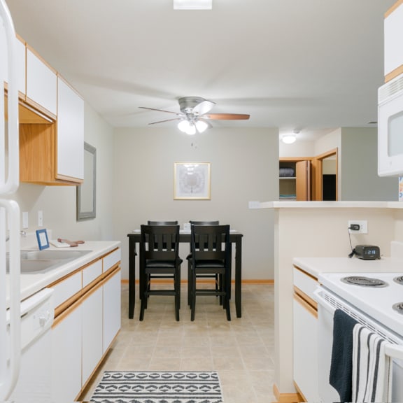 Thumbnail 7 of 20 a kitchen with white appliances and a dining room table with chairs in the back