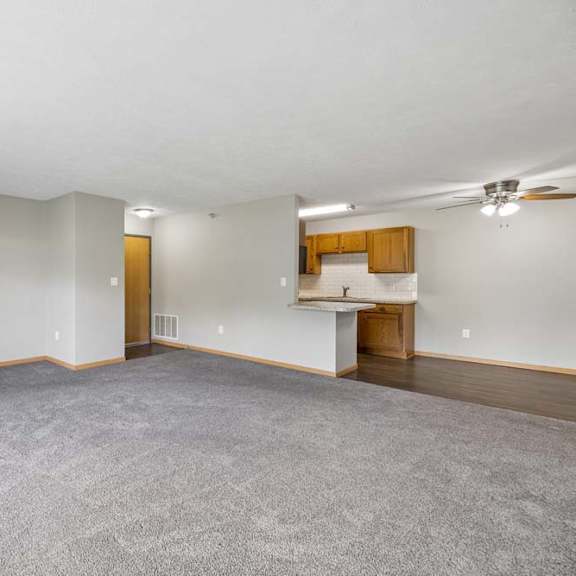 Thumbnail 5 of 13 Expansive apartment living room with plush carpeting, an open breakfast bar, and a connected dining area and kitchen.
