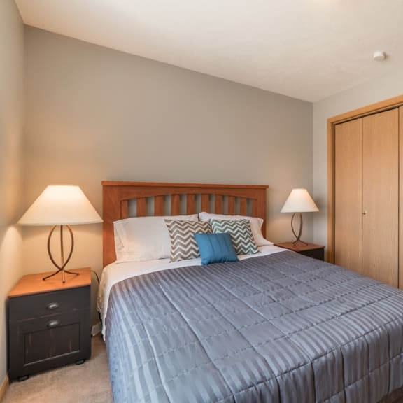 Thumbnail 7 of 10 room with bed, 2 nightstands with lamps, and bifold closet doors