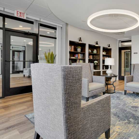 a resident clubhouse with gray chairs and a blue rug