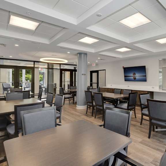 a common room with tables and chairs and a television on the wall
