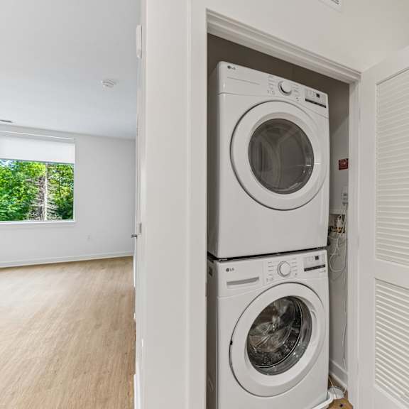 a white washing machine is in a white laundry room.