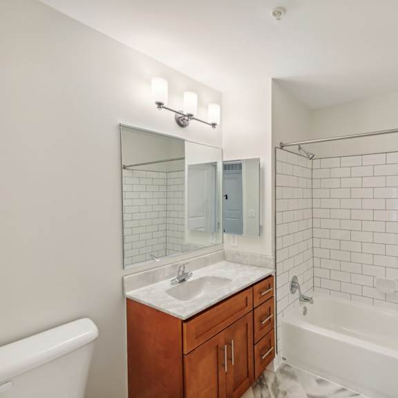 a white bathroom with a sink, mirror, and bathtub.