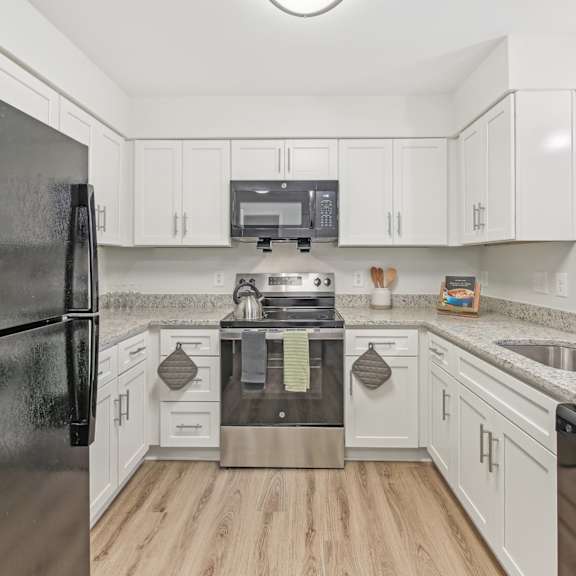 a kitchen with a black refrigerator and white cabinets.