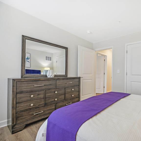 a bedroom with a bed, dresser, and mirror.