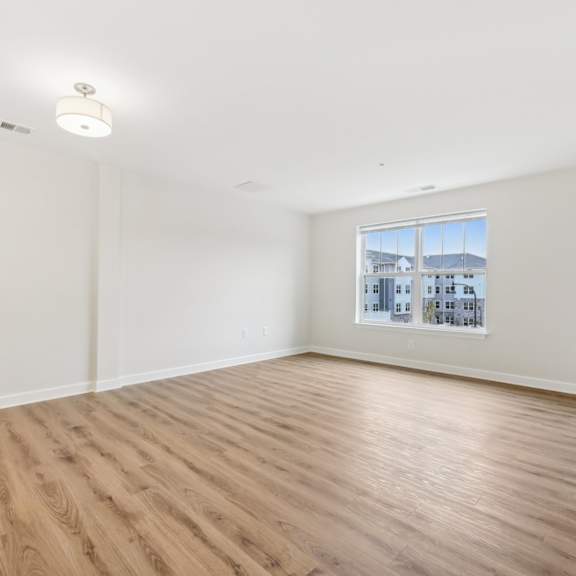 empty room with wooden floor and a window showing a cityscape outside.