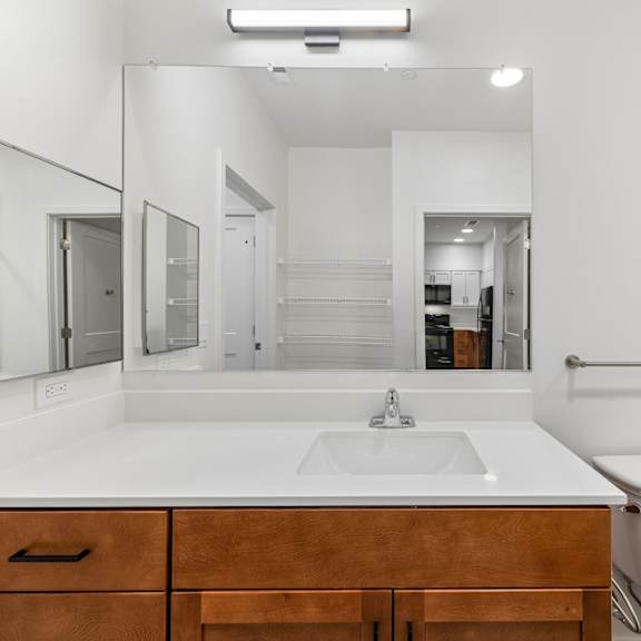 a white bathroom with a sink, toilet, and mirror.