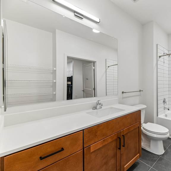 a white bathroom with a wooden vanity and a white bathtub.