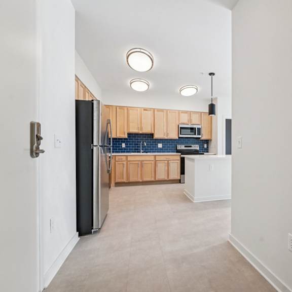 a kitchen with a black refrigerator and wooden cabinets.
