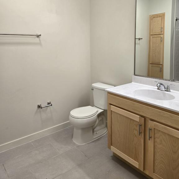 a bathroom with a toilet, sink, and mirror.