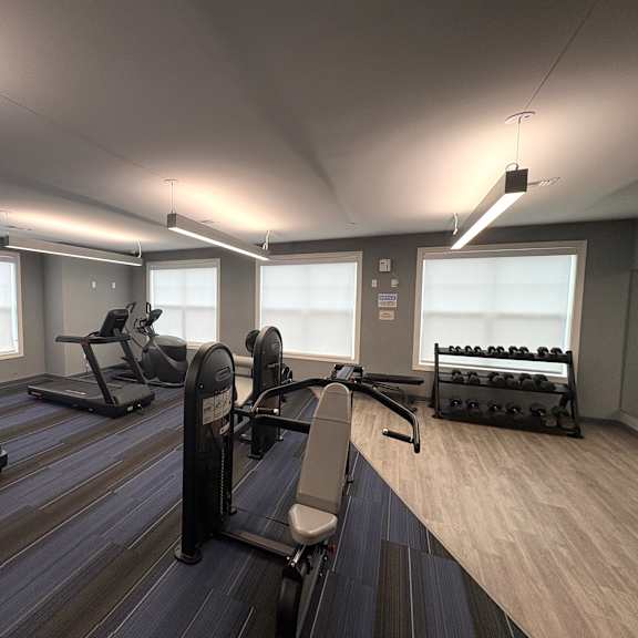 a gym with treadmills, elliptical machines, and dumbbells.