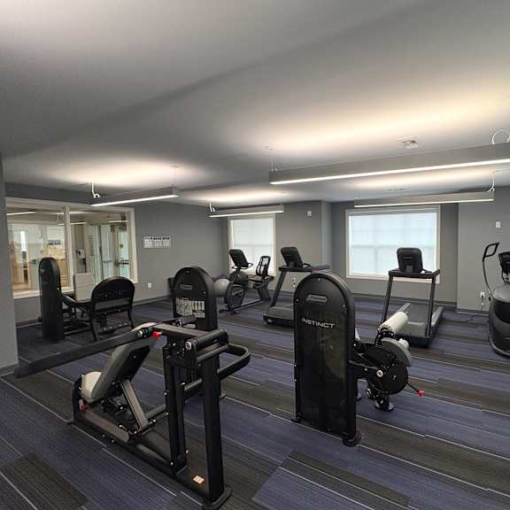 a gym with a variety of equipment including treadmills, stationary bikes, and elliptical machines.