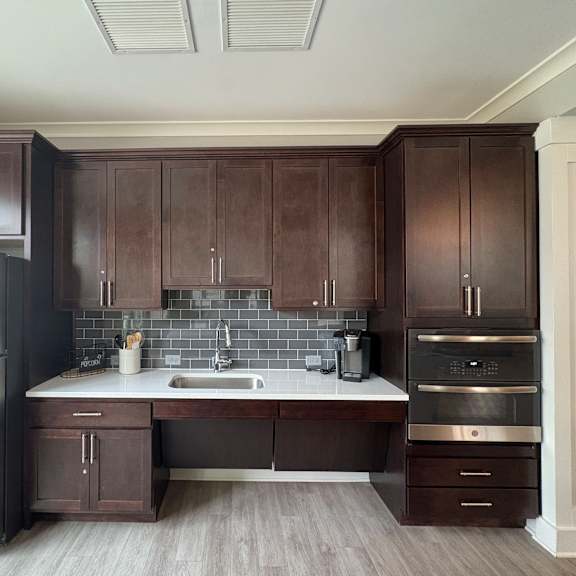 a kitchen with dark brown cabinets and a stainless steel refrigerator.