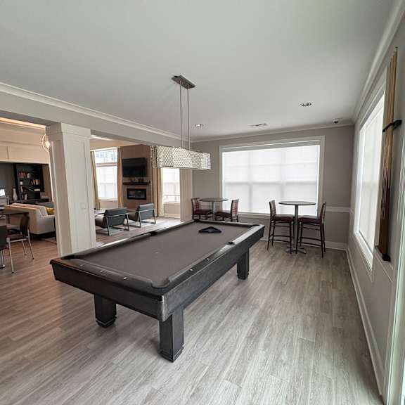 a pool table is in the middle of a room with a lot of windows.