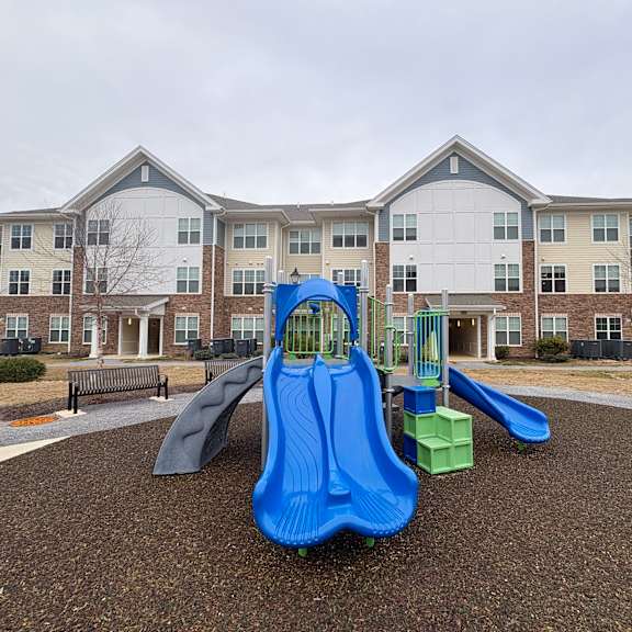 a playground with a blue slide in front of apartment buildings.