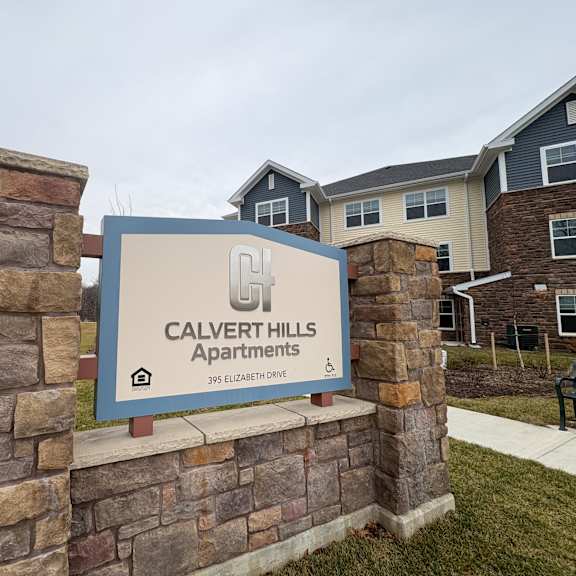 a sign for calvert hills apartments stands in front of a building.