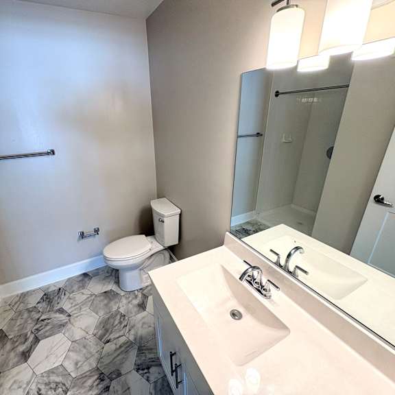 a bathroom with a toilet, sink, and mirror.