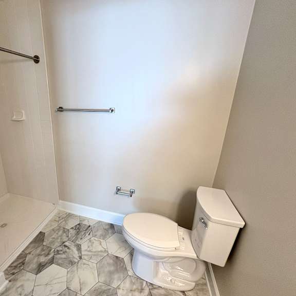 a white toilet sits next to a marble tiled floor in a bathroom.