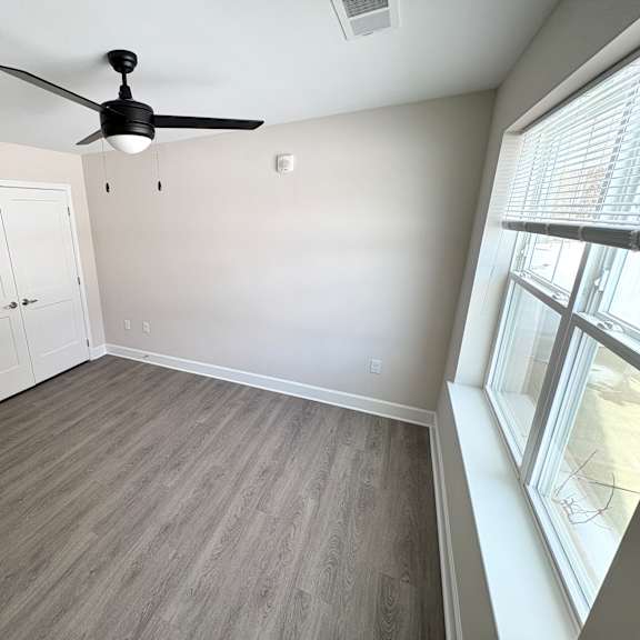 a room with a ceiling fan and a window with blinds.