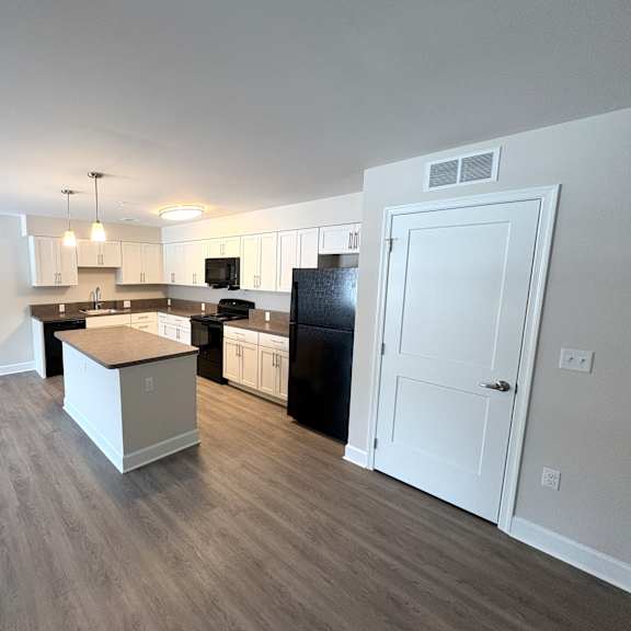 a kitchen with a black fridge and white cabinets.