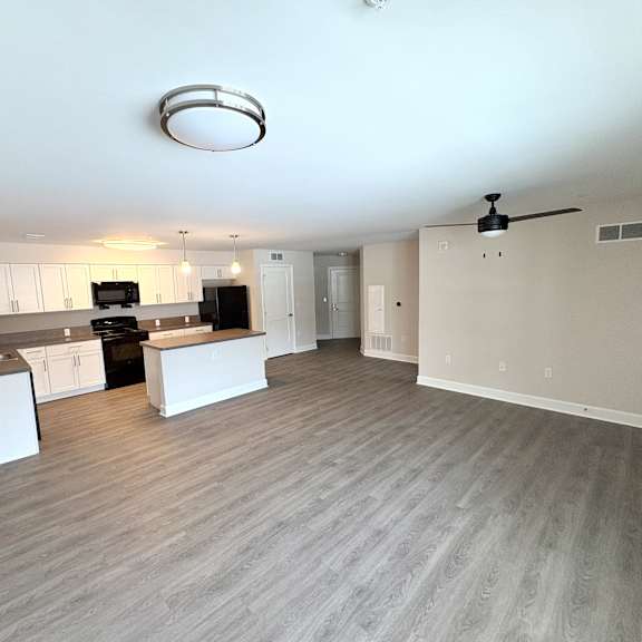 a spacious kitchen and living room with a ceiling fan and light fixture.
