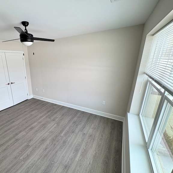 a room with a ceiling fan and a large window.