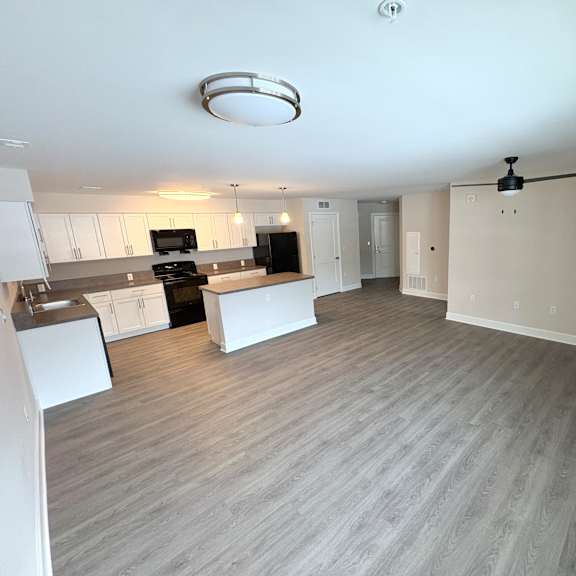 a spacious kitchen with a grey floor and white walls.