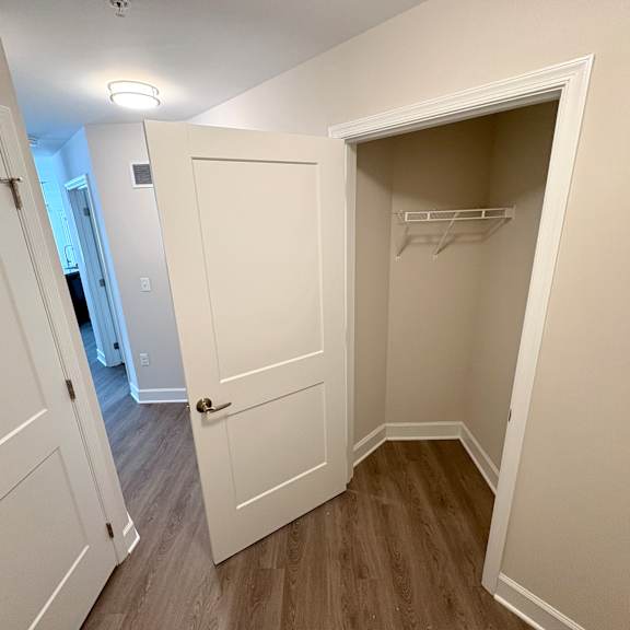a white closet with a shelf and a door open.