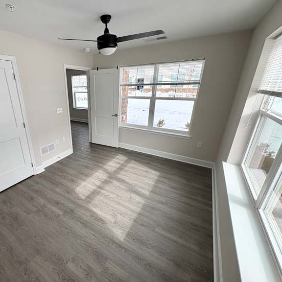 a room with a ceiling fan and a window with blinds.