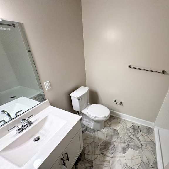 a bathroom with a toilet, sink, and a shower.