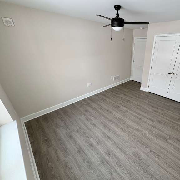 a room with a ceiling fan and a wooden floor.