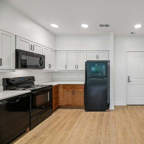 a kitchen with black appliances and wooden floors.