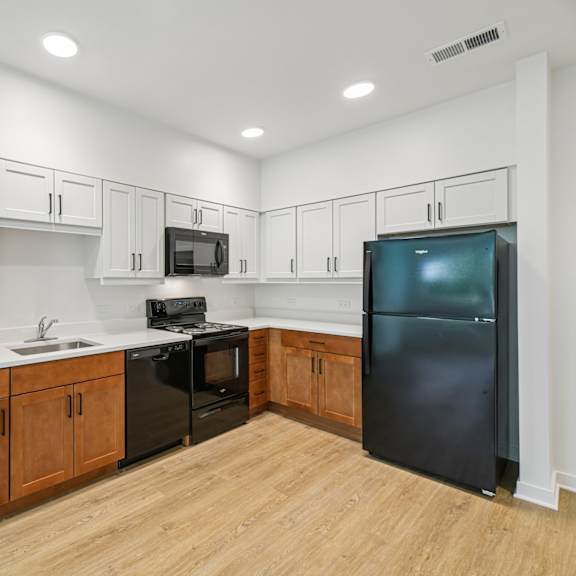a kitchen with wooden cabinets and a black refrigerator.