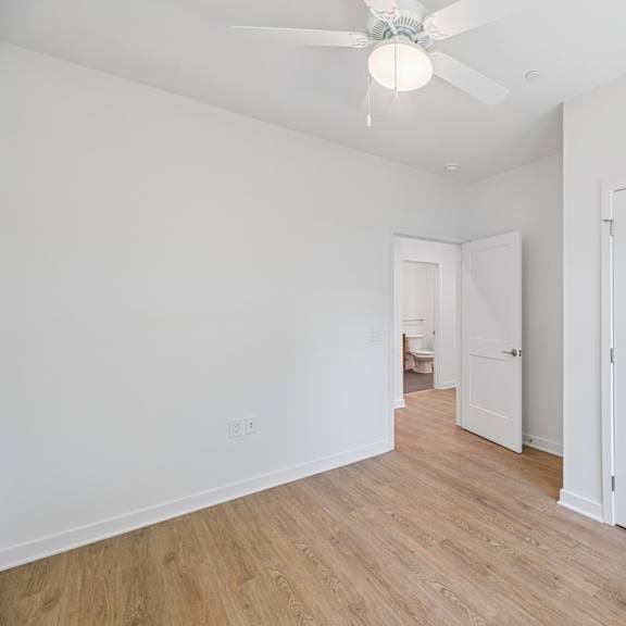 a room with a ceiling fan and white walls.