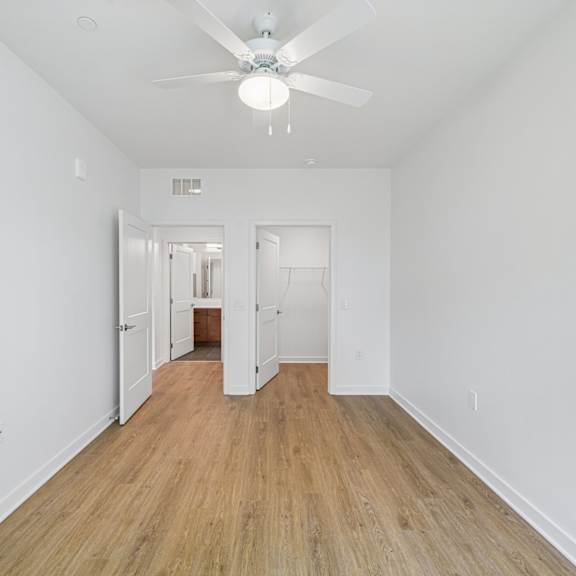 a room with a ceiling fan and wooden flooring.