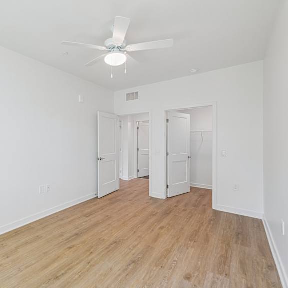 a room with a ceiling fan and wooden floors.
