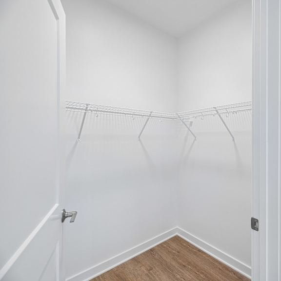 a white closet with a wooden floor and a white door.