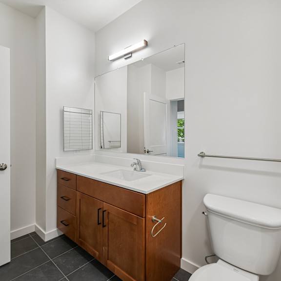 a white bathroom with a toilet, sink, and mirror.