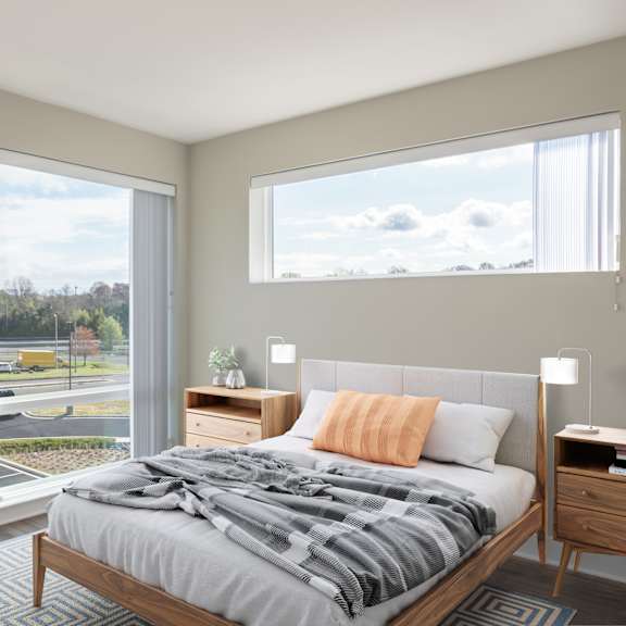 a bedroom with a large window and a bed with a blanket