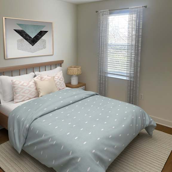 a bed with a blue comforter with white dots is in the foreground of a room with a window and a picture on the wall.