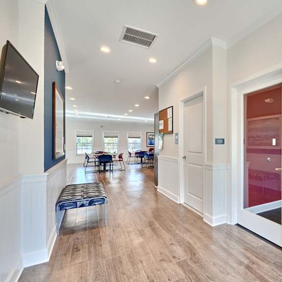 a long hallway with white walls and wood floors and a door to a dining room