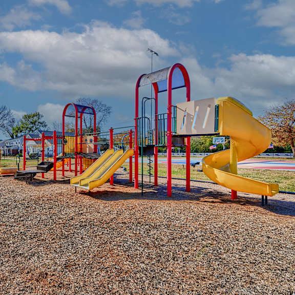 a playground at a park with yellow and red playsets