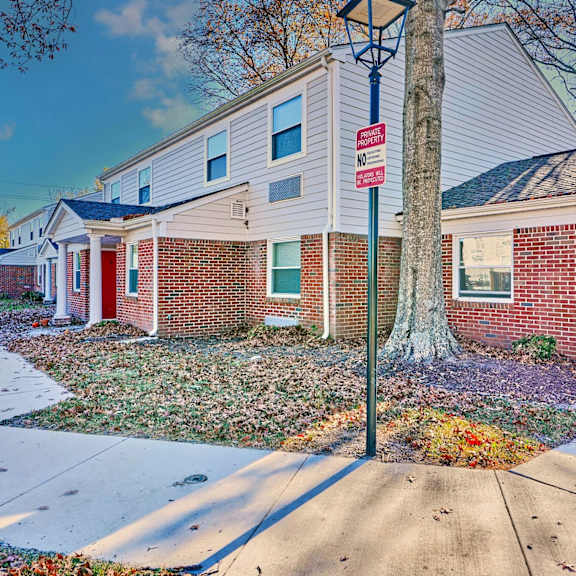 a red brick house with a street sign on the sidewalk