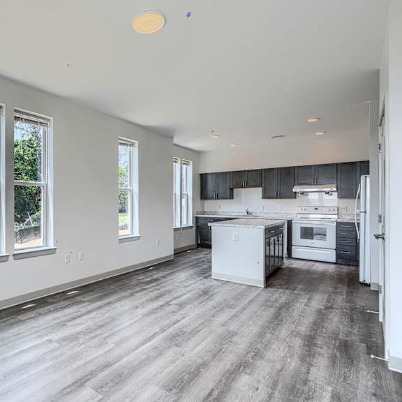 a spacious kitchen and living room with hardwood floors and large windows.