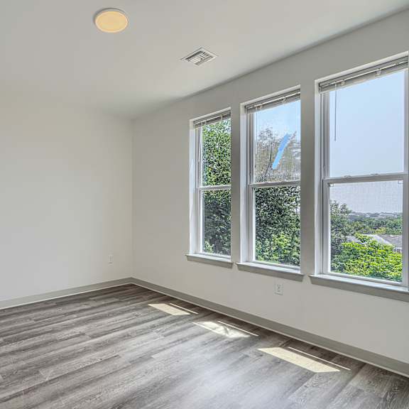 a room with a white door, a window, and a wooden floor.